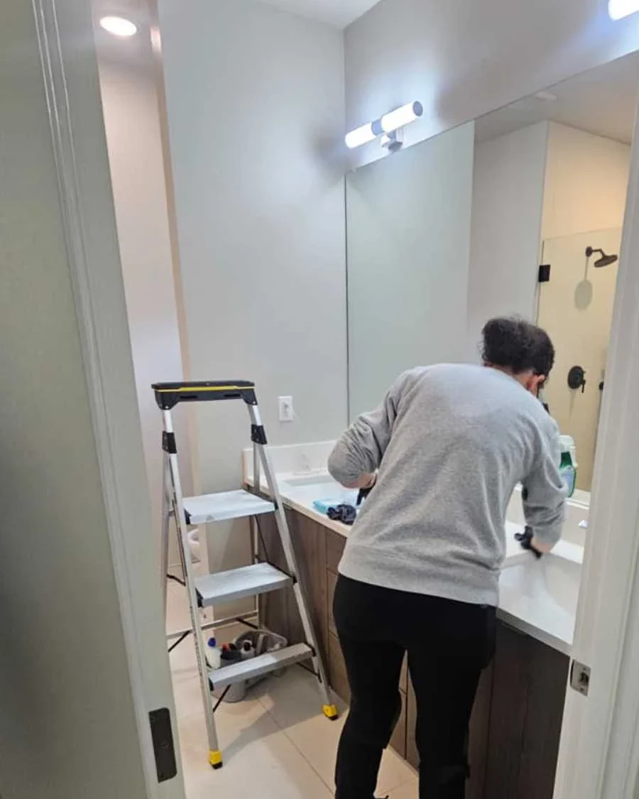 Cleaning professional working on a bathroom vanity during a detail-focused bathroom cleaning visit