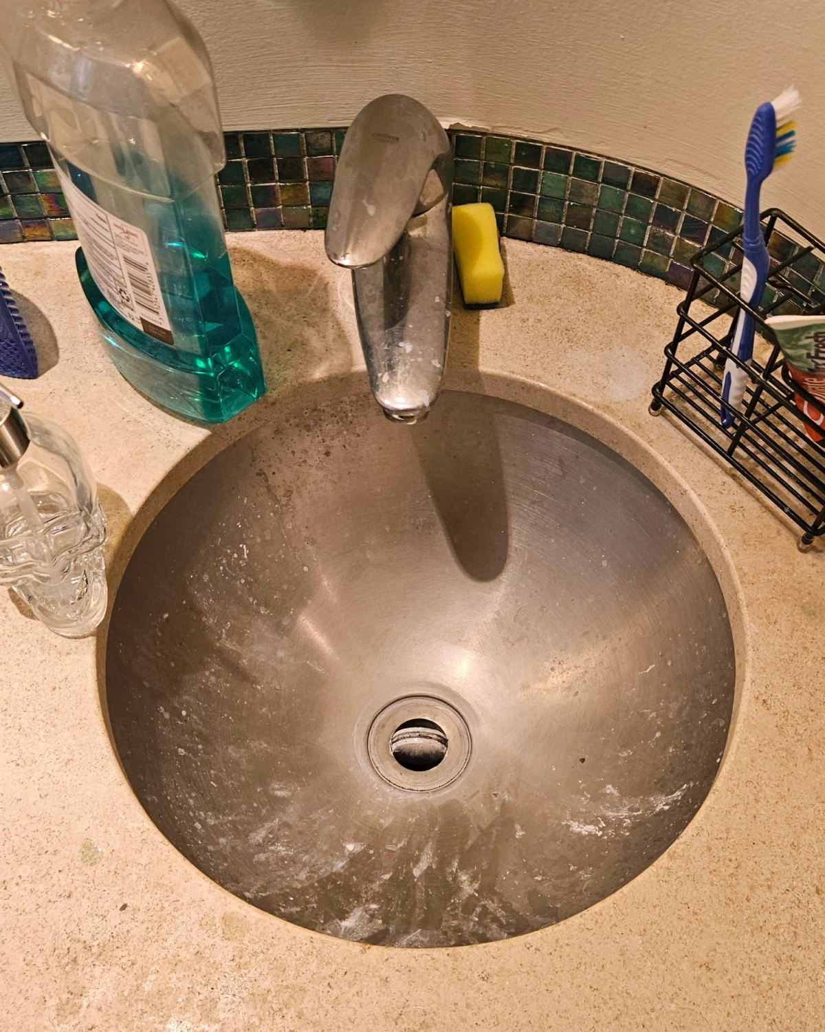 Stainless steel bathroom sink and faucet with visible soap residue and hard water deposits before deep cleaning