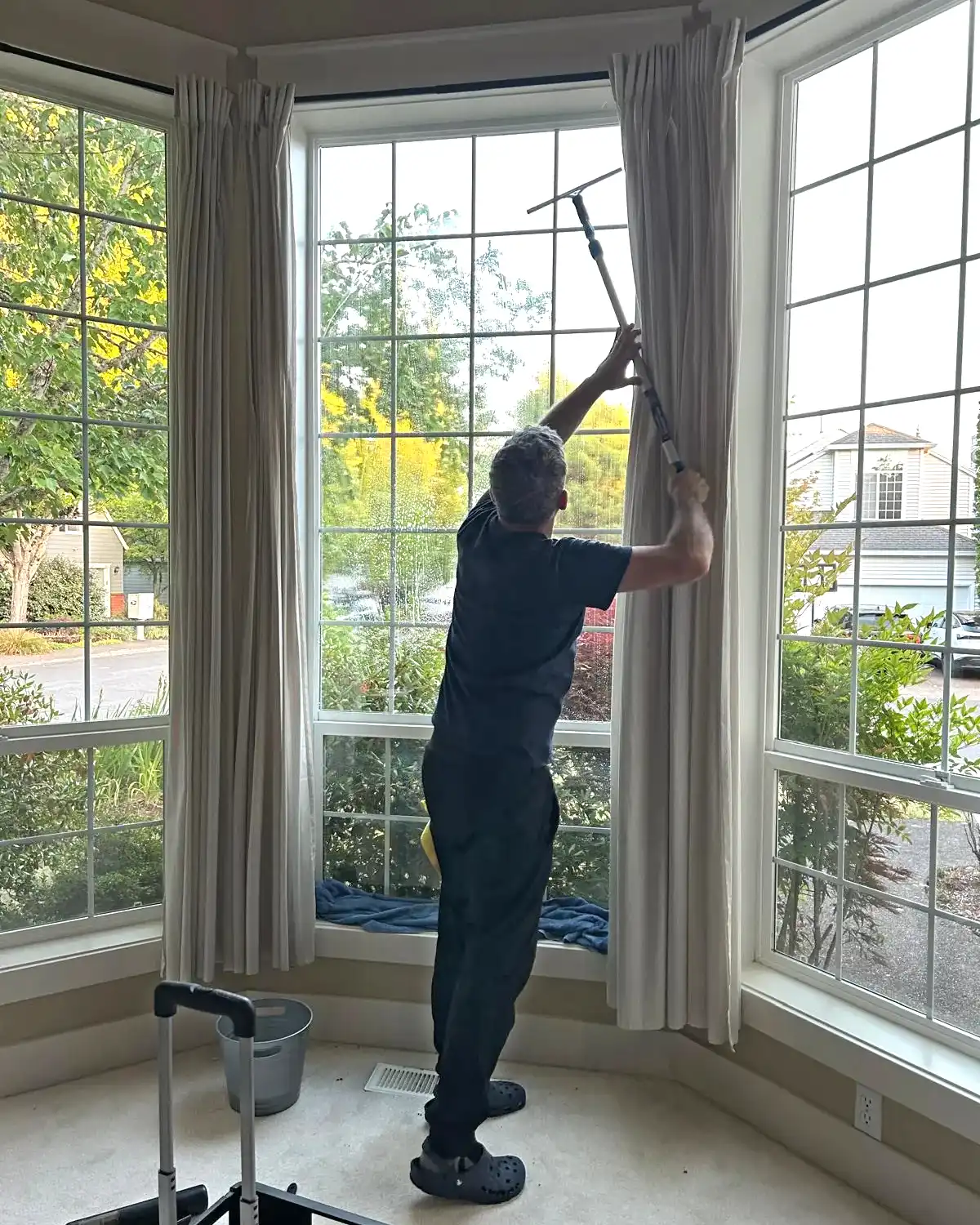 Daniel from Clary Clean cleaning tall interior windows during a residential cleaning visit