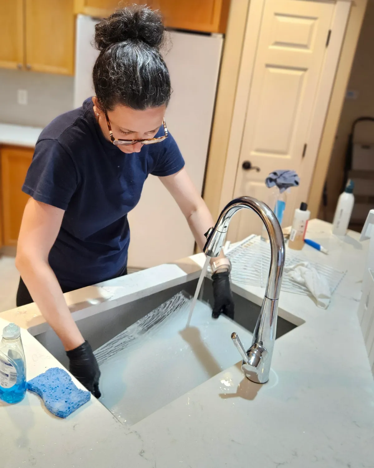 Camila from Clary Clean hand-cleaning a kitchen sink and surrounding counters during a residential cleaning visit