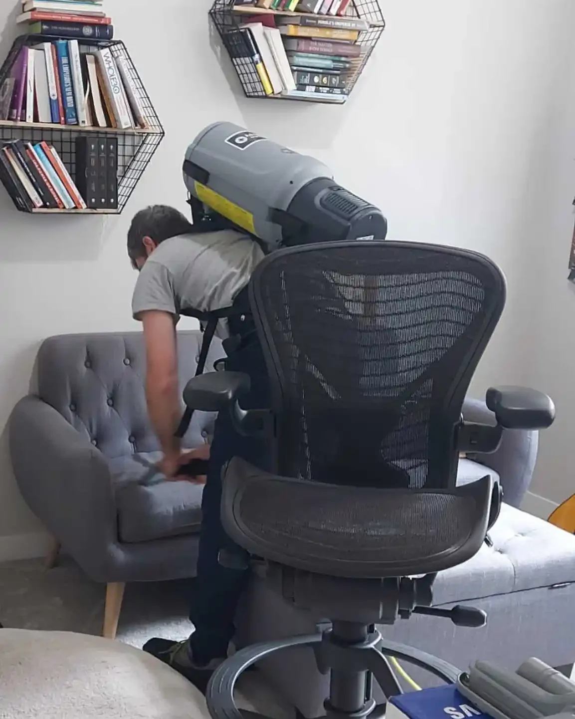 Cleaning professional vacuuming around seating and shelving during a home cleaning visit